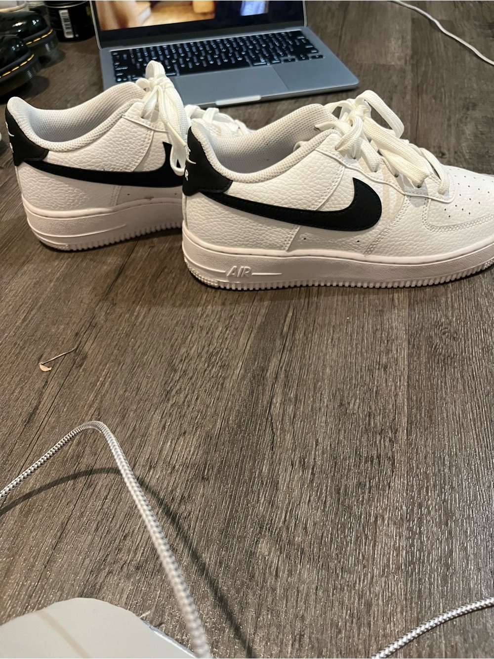 Nike Air Force 1 Low sneakers in white pebbled leather with a black swoosh.